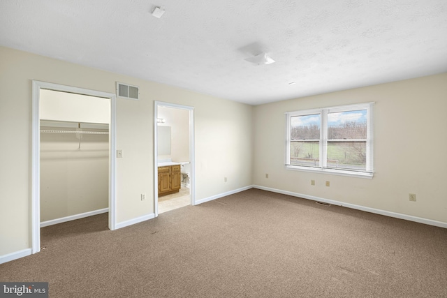 unfurnished bedroom featuring carpet flooring, a closet, and ensuite bathroom