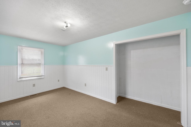 carpeted empty room with a textured ceiling