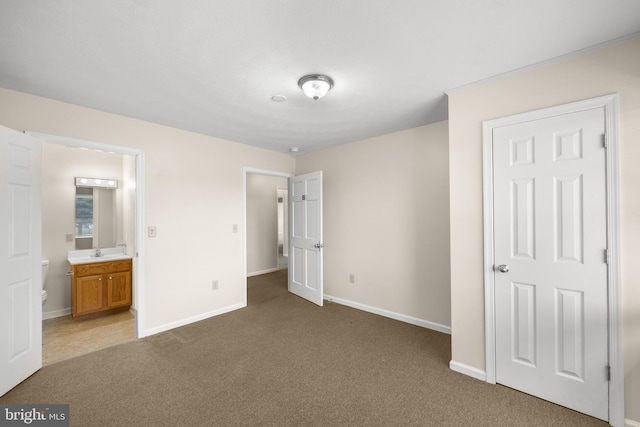 unfurnished bedroom featuring ensuite bath, sink, and dark colored carpet