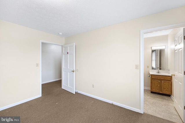 unfurnished bedroom featuring connected bathroom, a textured ceiling, and light colored carpet