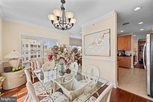 tiled dining space with crown molding and a notable chandelier