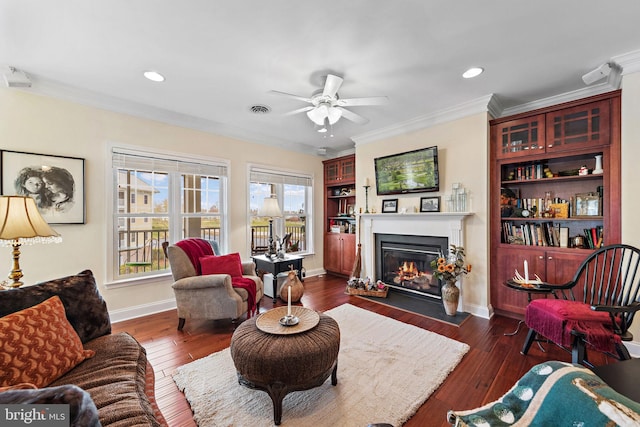 living room with a healthy amount of sunlight, ornamental molding, ceiling fan, and dark hardwood / wood-style floors