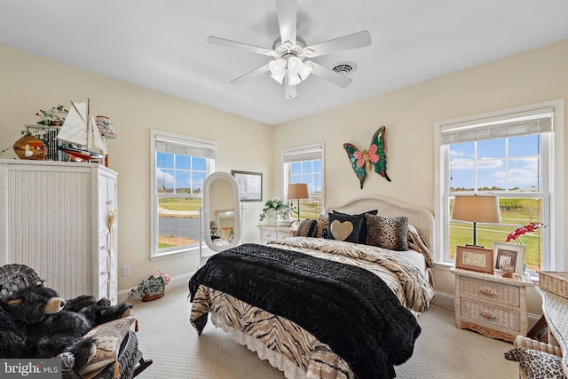 bedroom with light carpet, multiple windows, and ceiling fan