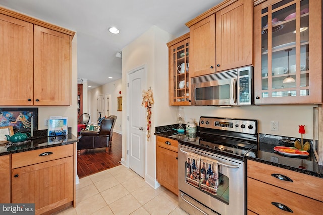 kitchen featuring appliances with stainless steel finishes, dark stone counters, and light tile floors