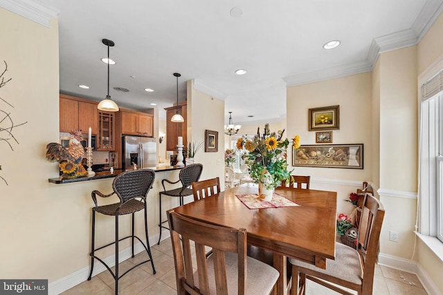 tiled dining room with ornamental molding and a chandelier