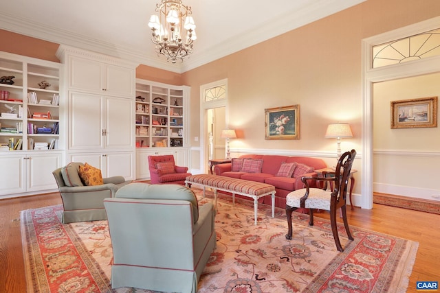 living room with built in features, light wood-type flooring, ornamental molding, and a chandelier