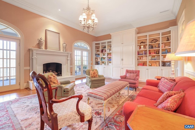 living room with an inviting chandelier, light hardwood / wood-style floors, french doors, and ornamental molding