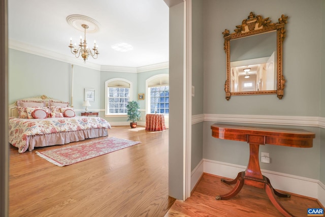 bedroom featuring light hardwood / wood-style floors, a notable chandelier, and crown molding