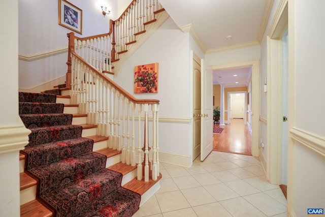 stairway with ornamental molding and light tile floors