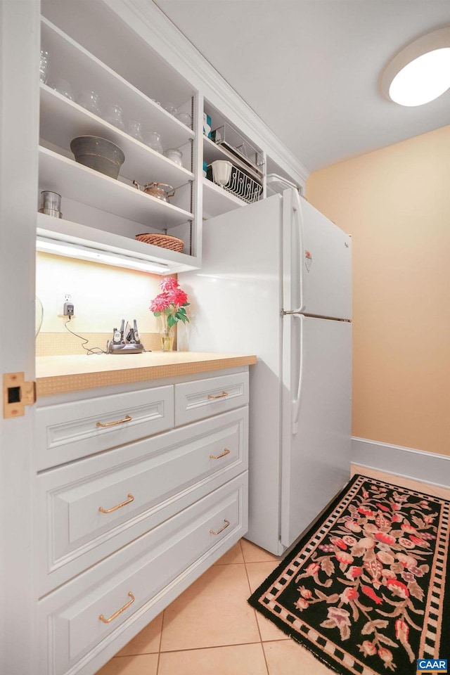 kitchen featuring white refrigerator, white cabinets, and light tile floors