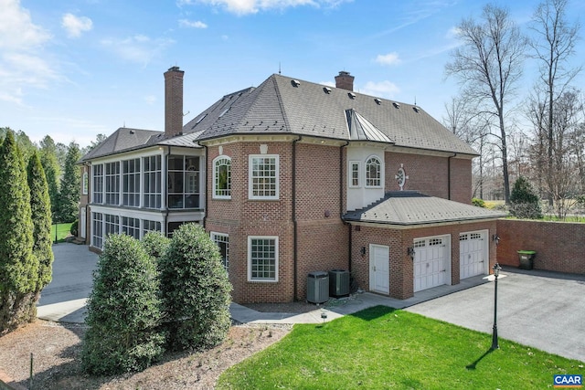 rear view of house with central AC, a sunroom, and a garage