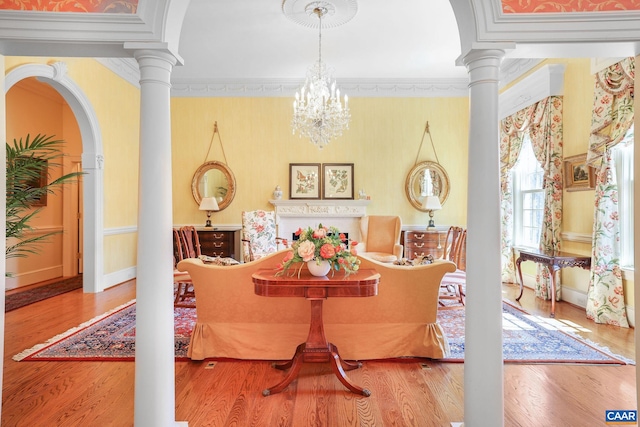 dining room with light hardwood / wood-style flooring, an inviting chandelier, ornamental molding, and ornate columns