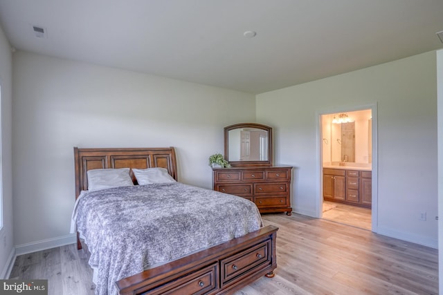 bedroom featuring light hardwood / wood-style flooring, sink, and ensuite bath