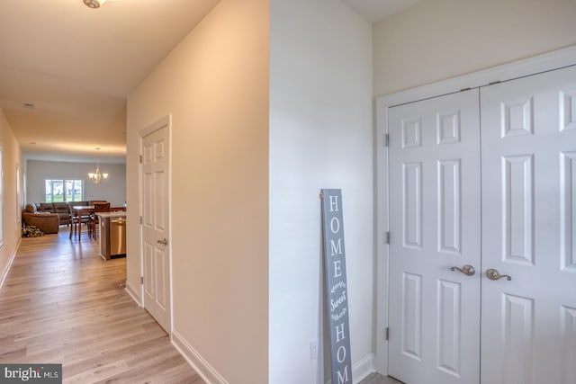 hall with a notable chandelier and light hardwood / wood-style floors