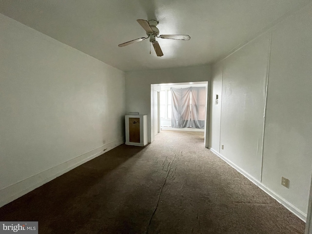 empty room with ceiling fan and dark colored carpet