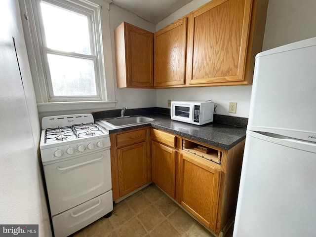 kitchen with plenty of natural light, white appliances, sink, and light tile floors