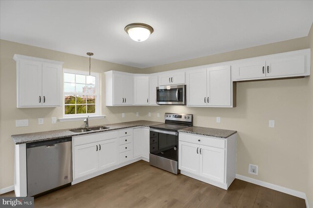 kitchen with stainless steel appliances, white cabinets, sink, decorative light fixtures, and wood-type flooring