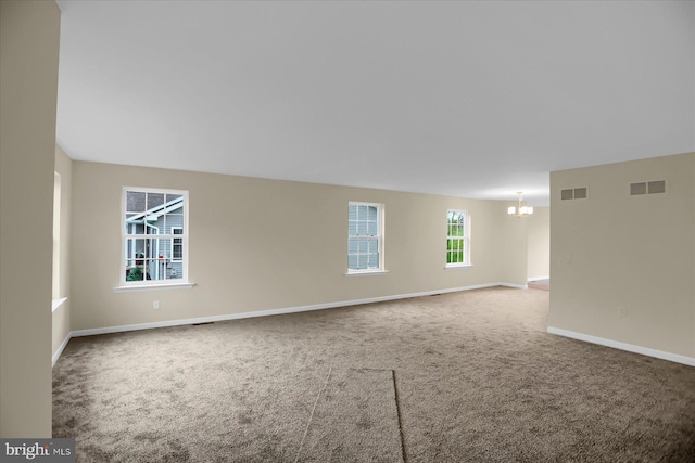 carpeted empty room with a chandelier