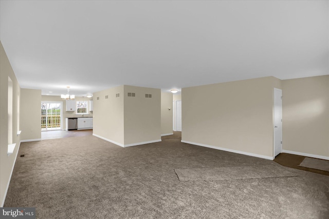 unfurnished living room with carpet floors and an inviting chandelier