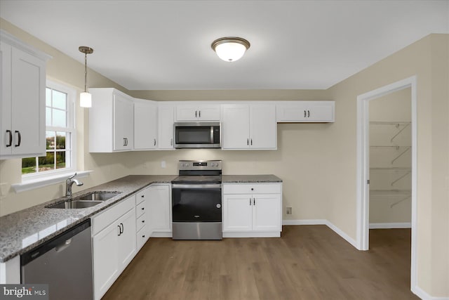 kitchen featuring white cabinetry, dark hardwood / wood-style floors, appliances with stainless steel finishes, pendant lighting, and sink