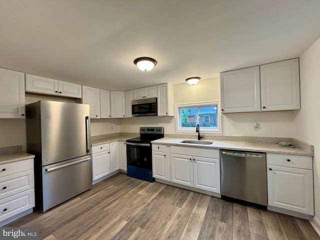 kitchen featuring sink, light wood-type flooring, stainless steel appliances, and white cabinetry