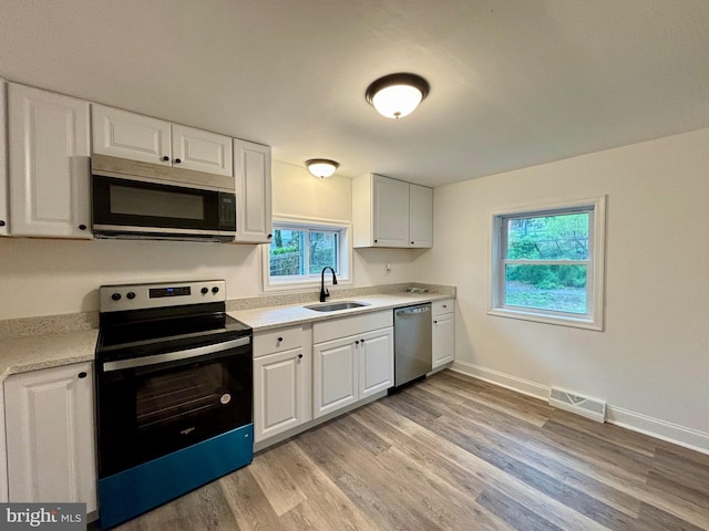 kitchen featuring white cabinets, sink, stainless steel appliances, and light hardwood / wood-style floors