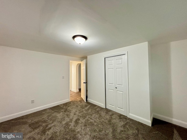 unfurnished bedroom featuring dark colored carpet and a closet