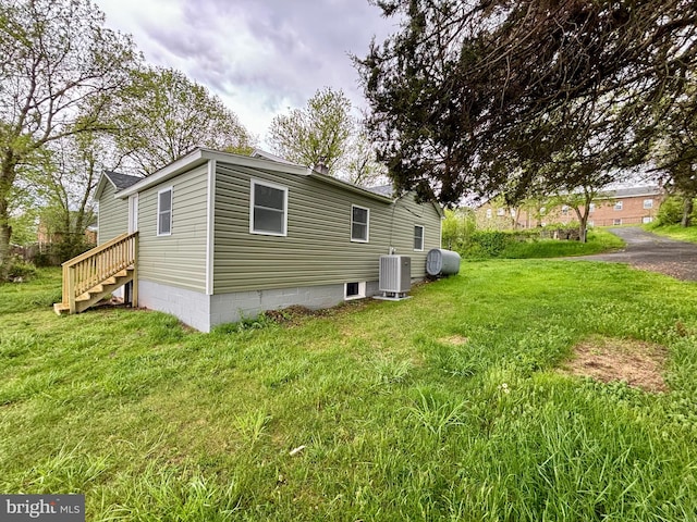 rear view of property with central AC unit and a lawn