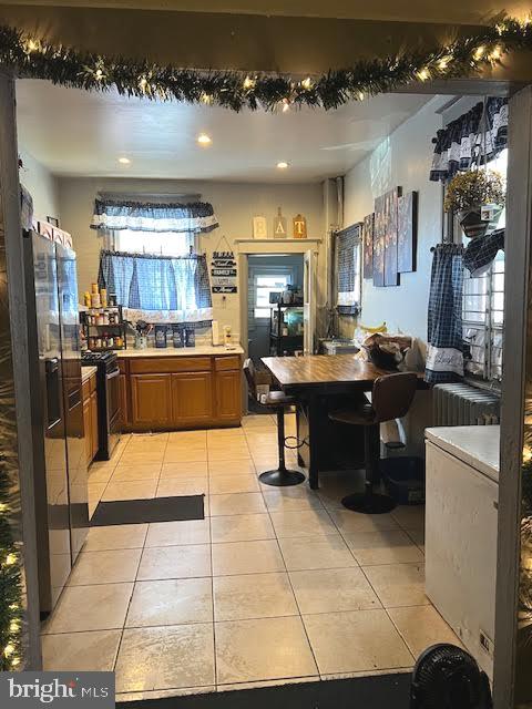 kitchen with stainless steel fridge, light tile floors, and range