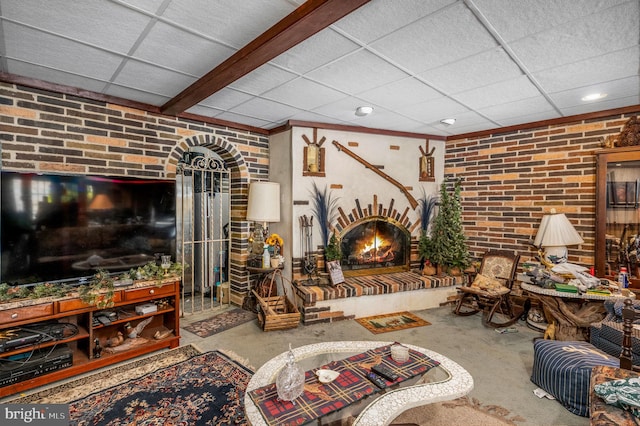 living room featuring concrete floors, brick wall, and a paneled ceiling