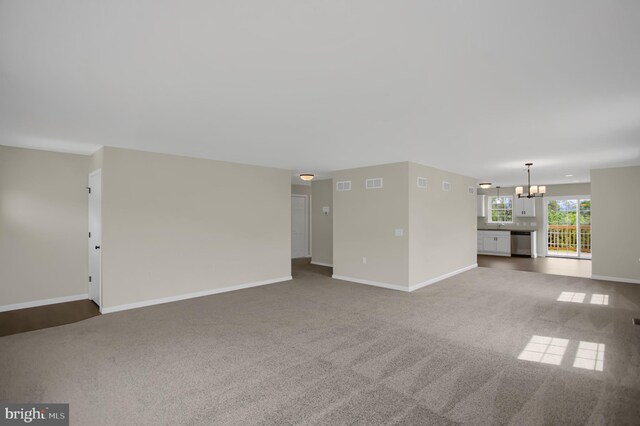 unfurnished living room with a chandelier and carpet