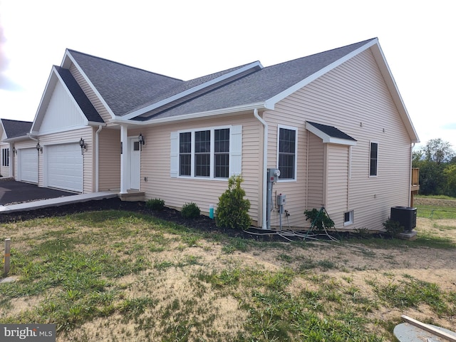 view of front of house featuring a garage, central AC unit, and a front yard