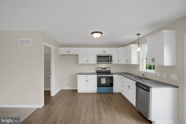 kitchen with hanging light fixtures, white cabinetry, appliances with stainless steel finishes, and sink