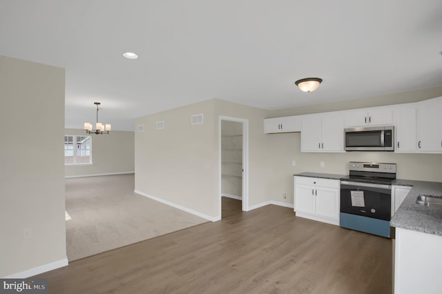 kitchen with appliances with stainless steel finishes, dark hardwood / wood-style floors, white cabinetry, hanging light fixtures, and a notable chandelier