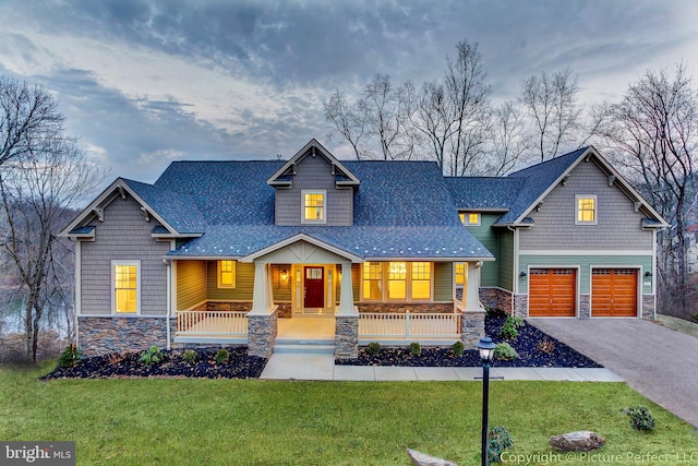 craftsman house featuring a front lawn, covered porch, and a garage