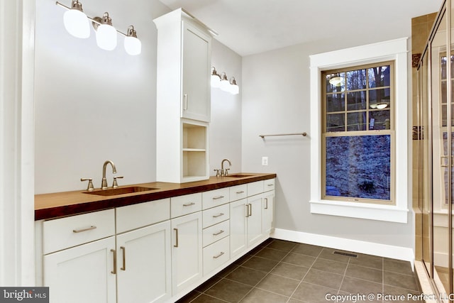 bathroom featuring a shower with shower door, dual vanity, and tile flooring