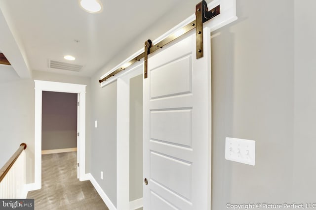 corridor with light colored carpet and a barn door