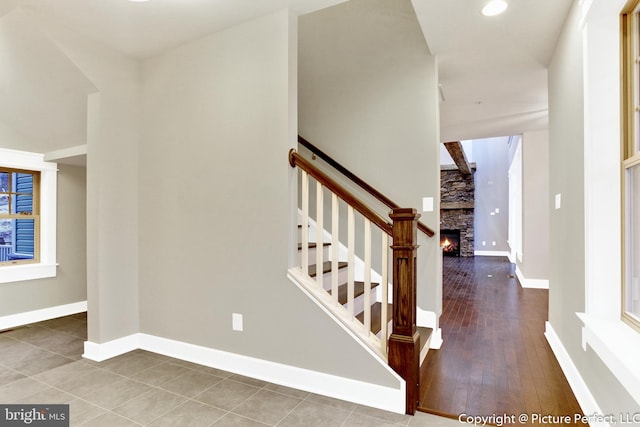 staircase featuring tile floors and a stone fireplace