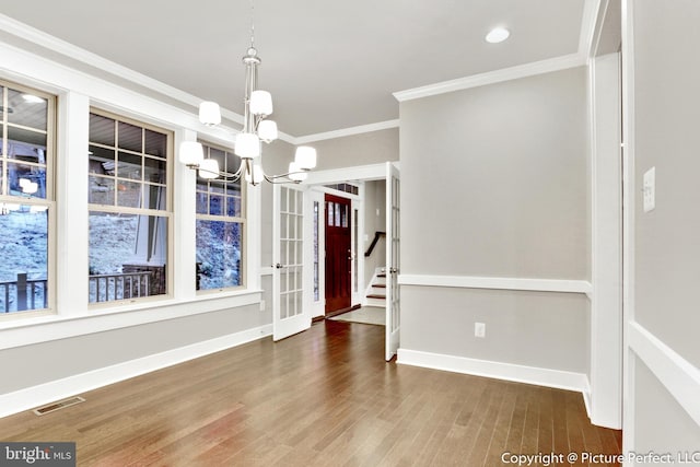 empty room featuring dark hardwood / wood-style flooring, crown molding, and a chandelier