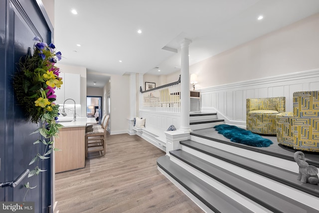 interior space with sink, decorative columns, and light wood-type flooring