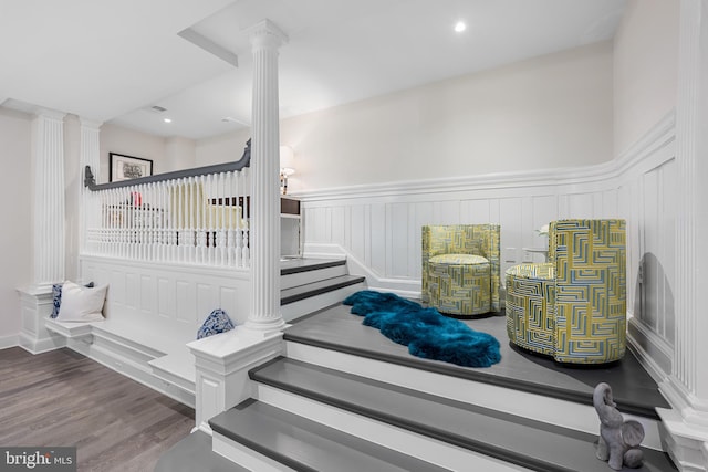 stairs featuring dark hardwood / wood-style flooring and decorative columns