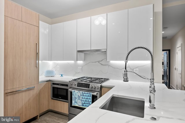 kitchen featuring hardwood / wood-style floors, sink, stainless steel appliances, white cabinets, and light stone counters