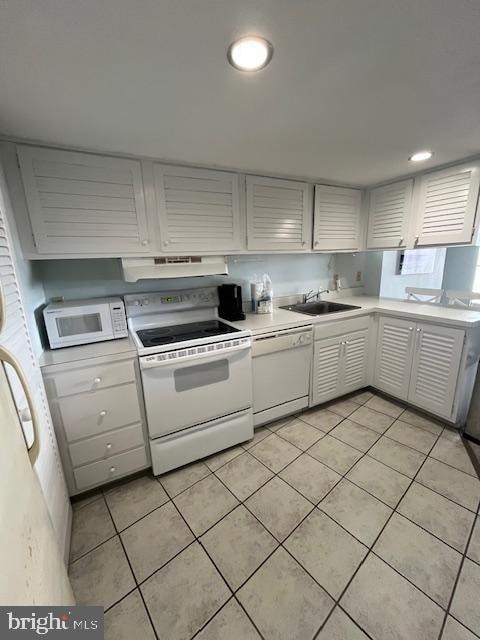 kitchen featuring white appliances, sink, and light tile floors