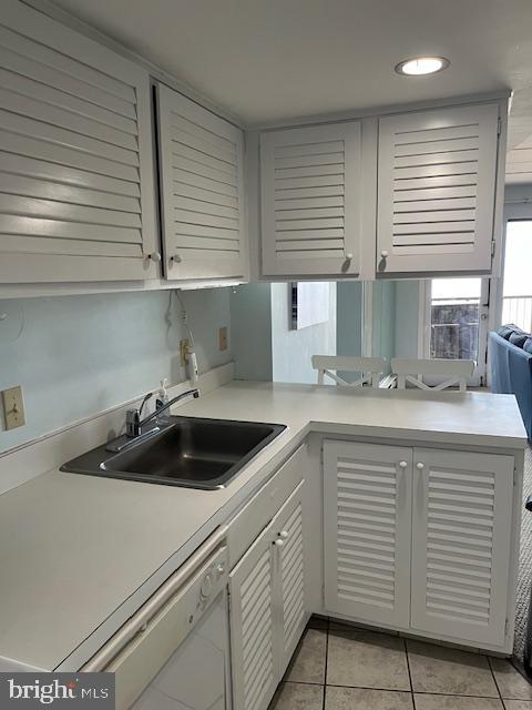 kitchen featuring white cabinets, sink, light tile flooring, and white dishwasher