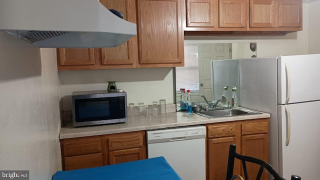 kitchen featuring white appliances, sink, and wall chimney exhaust hood