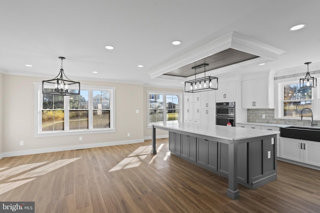 kitchen with decorative light fixtures, light stone countertops, white cabinets, and a center island