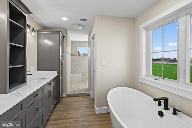 bathroom with hardwood / wood-style flooring, vanity, and shower with separate bathtub