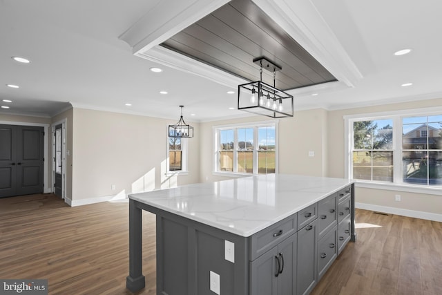 kitchen featuring hanging light fixtures, light stone counters, gray cabinets, hardwood / wood-style floors, and ornamental molding