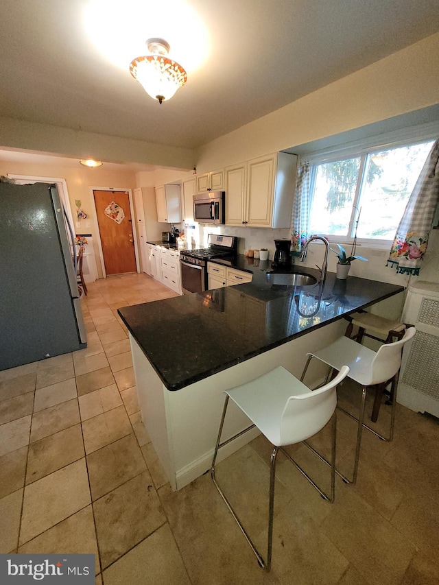 kitchen with white cabinetry, light tile floors, stainless steel appliances, and kitchen peninsula