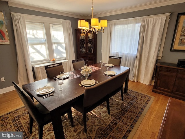 dining space featuring light hardwood / wood-style flooring, crown molding, and a notable chandelier